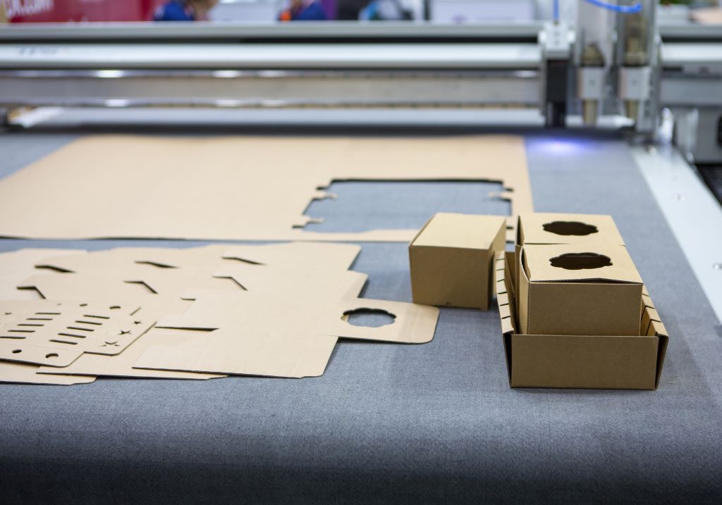 Digital die cut machine cutting corrugated cardboard products. Industrial manufacture.