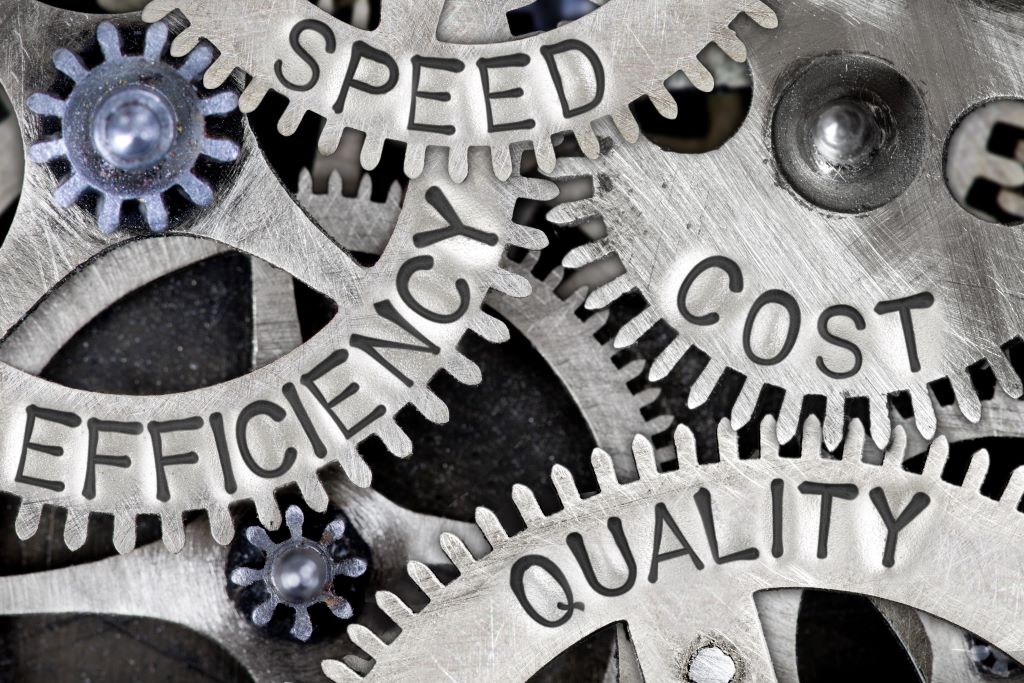 Close-up of interlocking metal gears engraved with the words "Speed," "Efficiency," "Cost," and "Quality," symbolizing operational synergy.